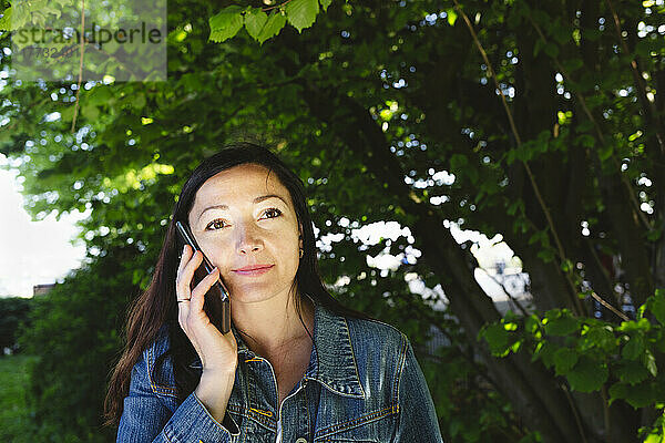 Frau spricht im Park mit Smartphone