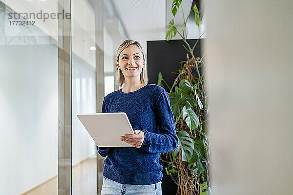 Lächelnde Geschäftsfrau mit digitalem Tablet im Büro