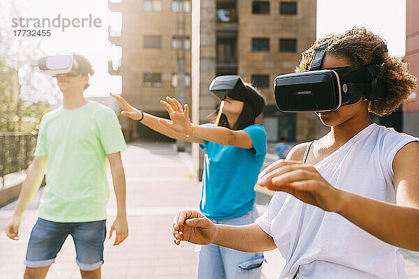 Gemischtrassige Freunde tragen an einem sonnigen Tag einen Virtual-Reality-Simulator