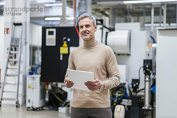 Reifer Geschäftsmann hält digitales Tablet in der Fabrik