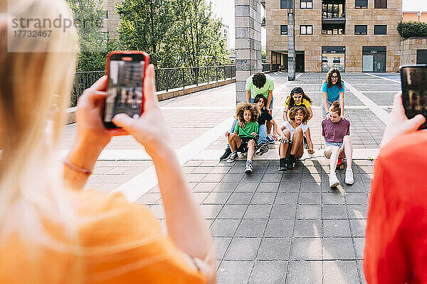 Mädchen mit Smartphone filmt Freunde beim Genießen auf dem Parkplatz