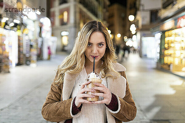 Junge Frau trinkt aus Einwegbecher auf der Straße in der Stadt