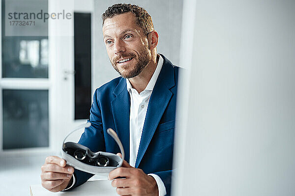 Lächelnder Geschäftsmann mit Virtual-Reality-Headset im Büro