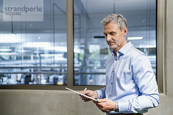 Geschäftsmann nutzt digitales Tablet im Fabrikbüro