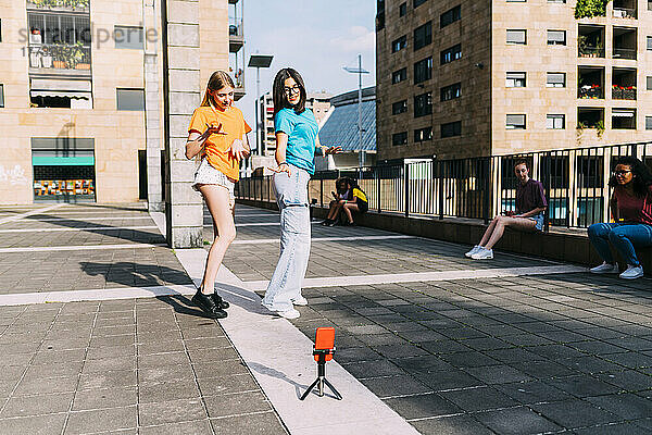 Mädchen tanzen und filmen an einem sonnigen Tag mit dem Smartphone