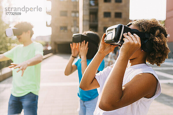 Freunde tragen an einem sonnigen Tag einen Virtual-Reality-Simulator