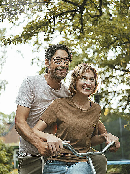 Glücklicher reifer Mann und Frau  die gemeinsam im Hinterhof Fahrrad fahren