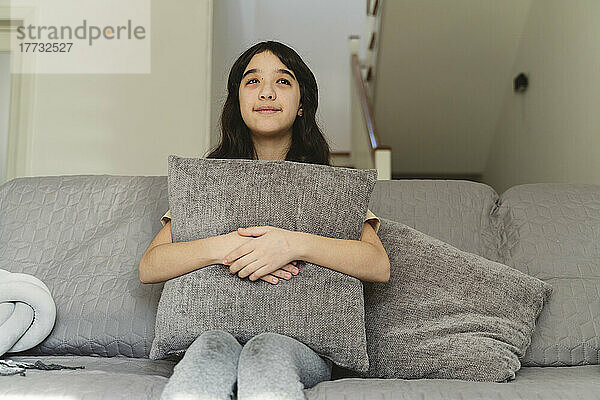 Girl day dreaming sitting on sofa