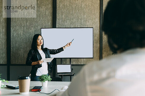 Mature businesswoman giving presentation to colleague at office