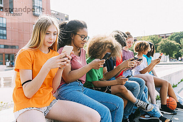 Freunde surfen an einem sonnigen Tag über Smartphones im Internet
