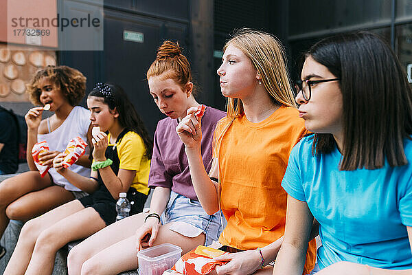 Mädchen sitzen zusammen und essen Snacks