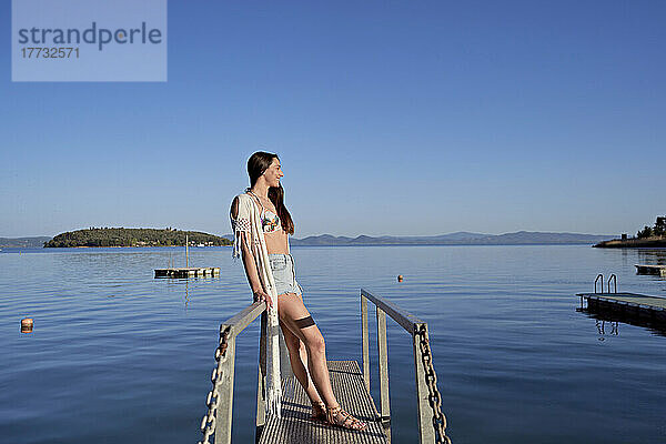 Lächelnde Frau steht auf dem Steg über dem See