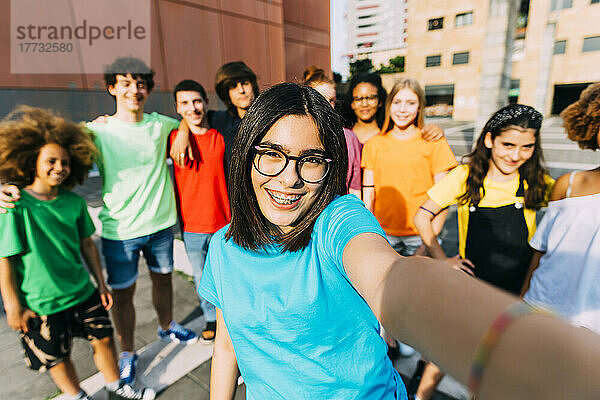 Lächelndes Mädchen mit Brille macht Selfie mit Freunden