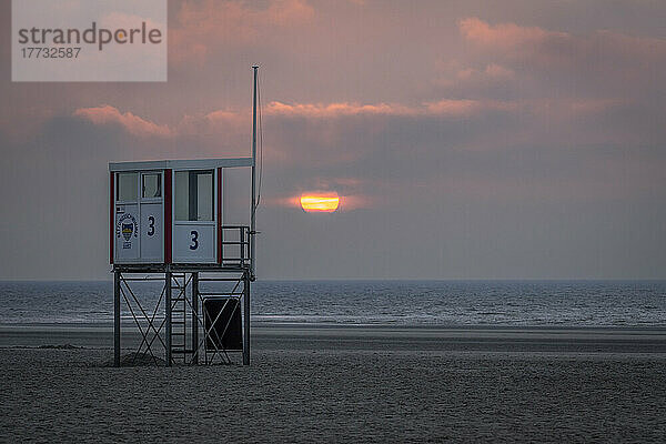 Rettungsschwimmerhütte am leeren Strand bei Sonnenuntergang