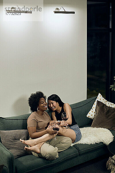 Lesbisches Paar lacht zu Hause gemeinsam auf dem Sofa