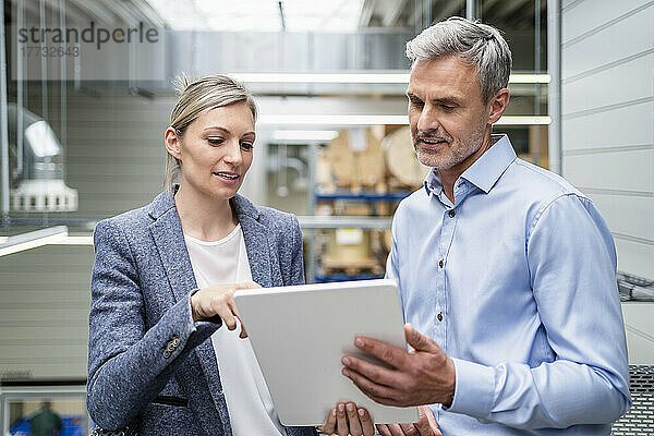 Geschäftsmann und Geschäftsfrau teilen sich digitales Tablet in der Fabrik