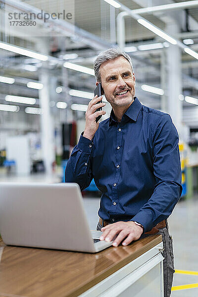 Mature businessman on the phone in factory