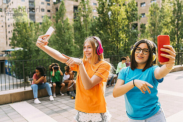 Fröhliche Mädchen mit kabellosen Kopfhörern filmen per Smartphone