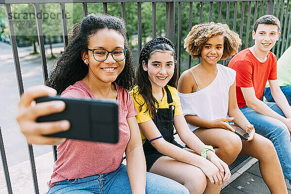 Glückliche junge Frau  die per Smartphone ein Selfie mit Freunden macht
