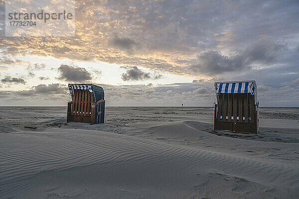 Deutschland  Niedersachsen  Juist  Strandkörbe mit Kapuze am leeren Strand bei Sonnenuntergang