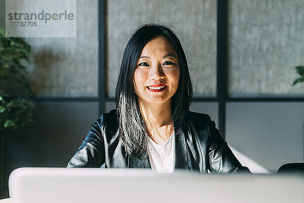 Lächelnde Geschäftsfrau mit Laptop im Büro
