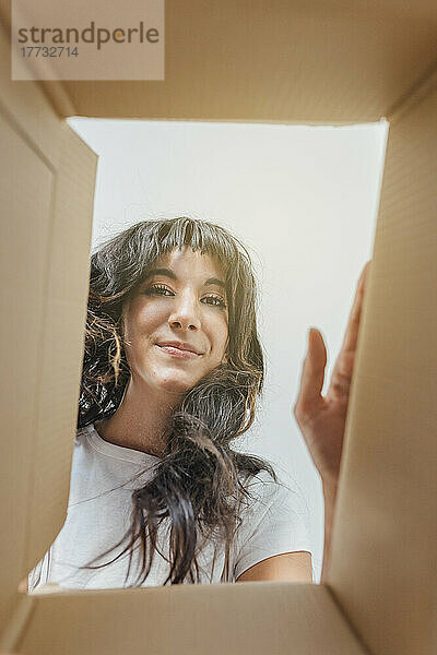 Lächelnde Frau durch Karton gesehen