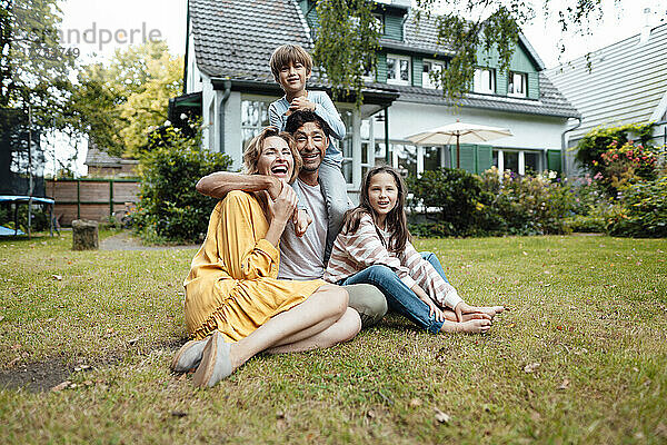 Happy family sitting in front of house at back yard