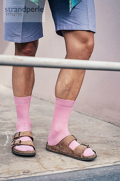 Beine eines Mannes mit rosa Socken und Sandalen