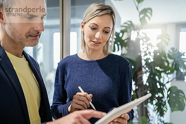 Geschäftsmann und Geschäftsfrau teilen sich im Büro ein digitales Tablet