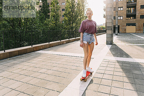 Teenagermädchen fährt an einem sonnigen Tag Skateboard