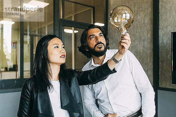 Mature business colleagues analyzing light bulb at office