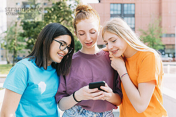 Teenage girl sharing smart phone with friends