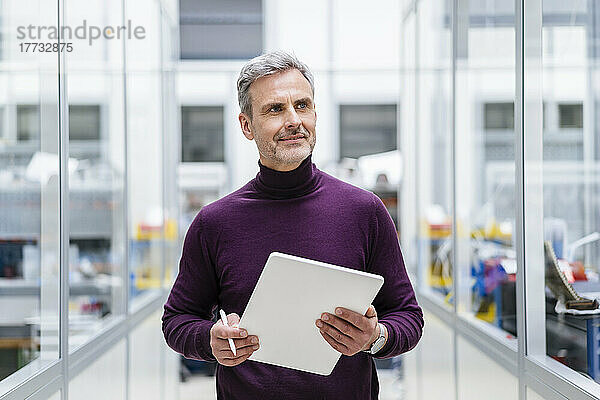 Reifer Geschäftsmann hält digitales Tablet in der Fabrik