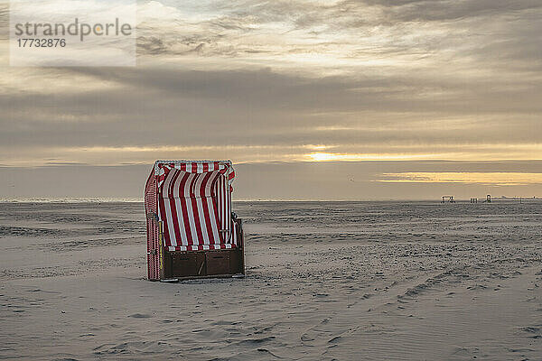 Deutschland  Niedersachsen  Juist  Strandkorb mit Kapuze am leeren Strand bei Sonnenuntergang