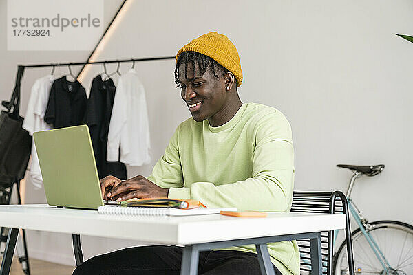 Lächelnder Geschäftsmann  der im Heimbüro am Laptop arbeitet