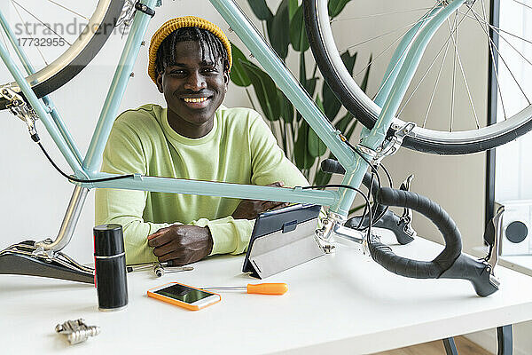 Lächelnder Vlogger mit Fahrrad auf dem Tisch zu Hause