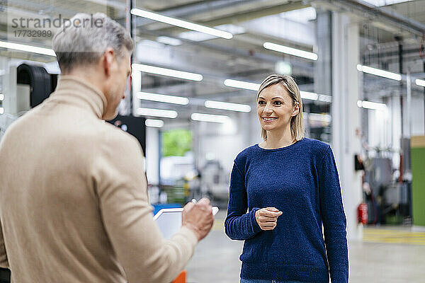 Geschäftsfrau lächelt Kollegen in der Fabrik an