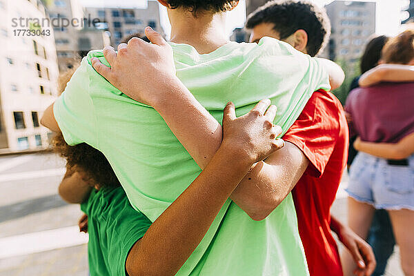Gemischtrassige Freunde umarmen sich auf dem Fußweg
