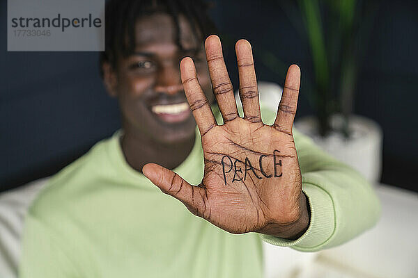 Smiling man showing peace written on palm of hand