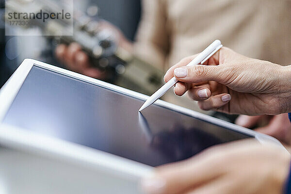 Nahaufnahme einer Geschäftsfrau  die einen digitalisierten Stift auf einem Tablet verwendet