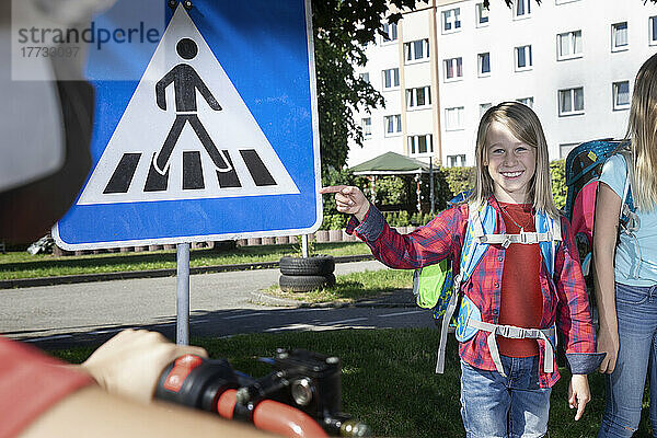 Smiling boy pointing at pedestrian sign