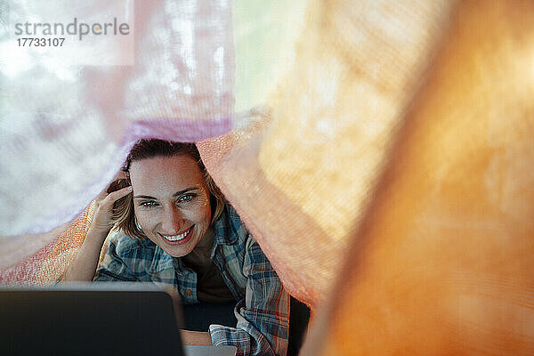 Mature woman using laptop under blanket