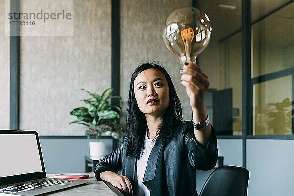 Businesswoman analyzing light bulb at office