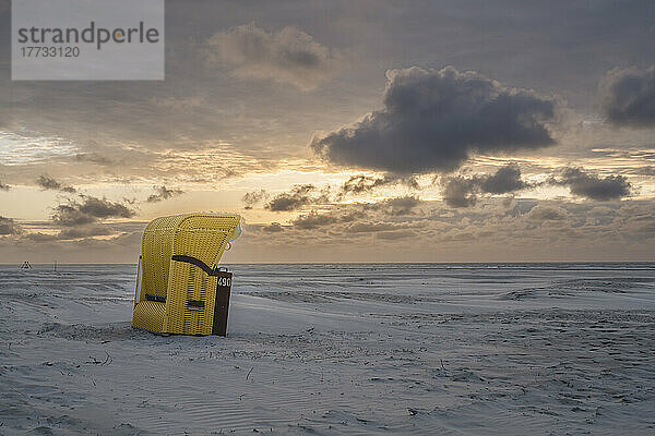 Deutschland  Niedersachsen  Juist  Strandkorb mit Kapuze am leeren Strand bei Sonnenuntergang