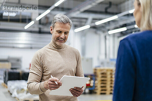 Lächelnder Geschäftsmann mit digitalem Tablet und Geschäftsfrau in der Fabrik