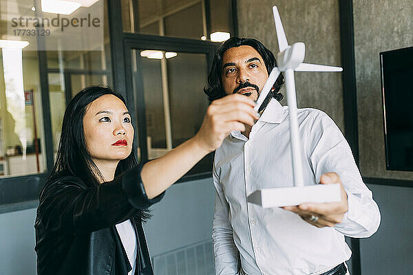 Business people analyzing wind turbine model at office