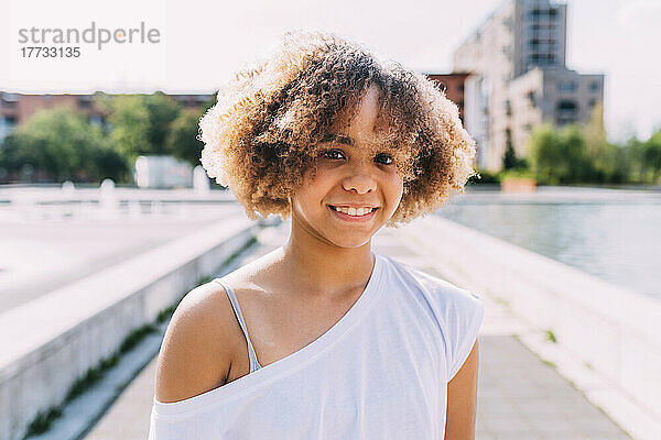 Fröhliches Mädchen mit Afro-Frisur an einem sonnigen Tag