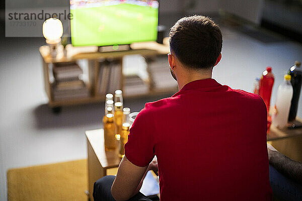 Junger Mann schaut sich zu Hause ein Fußballspiel an