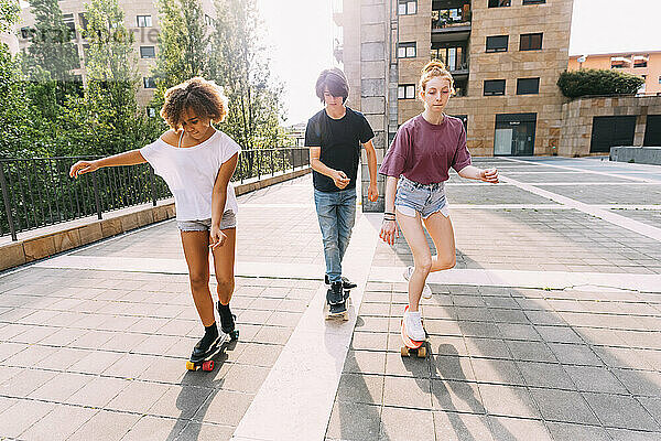 Freunde fahren an einem sonnigen Tag gemeinsam auf dem Parkplatz Skateboard