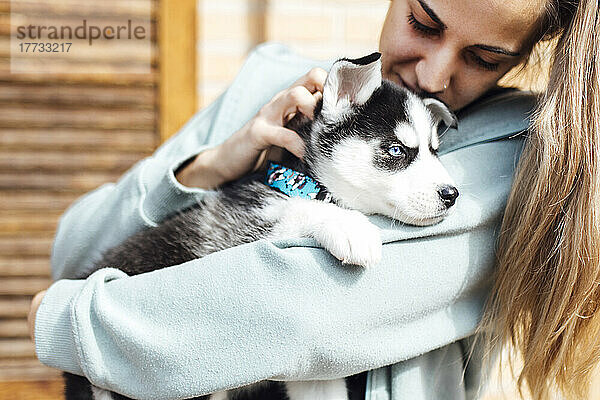 Young woman stroking husky puppy